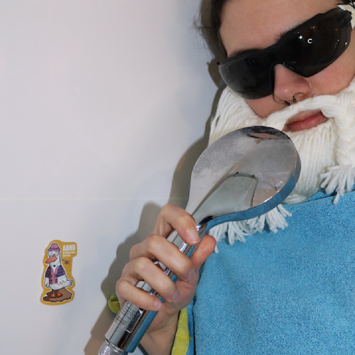 Sticker “ADHD - All Ducks Have Diarrhea” in a shower scene with the Crafting Wizard in a towel holding the shower head like a microphone, sticker on the wall in a funny staged setup.