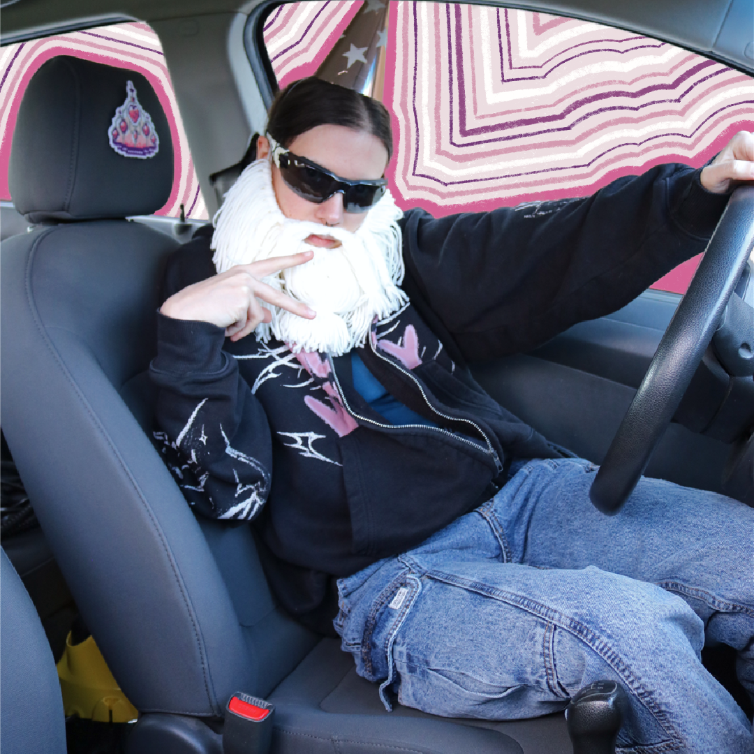 Cross-stitch Barbie Crown placed on a car seat neck support for a “passenger princess” setup, with the Crafting Wizard present, a humorous staged scene.