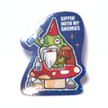Sticker of a drunk gnome frog sitting on a large mushroom, raising a bottle, with many bottles below and the slogan ‘Sippin’ With My Gnomies.’
