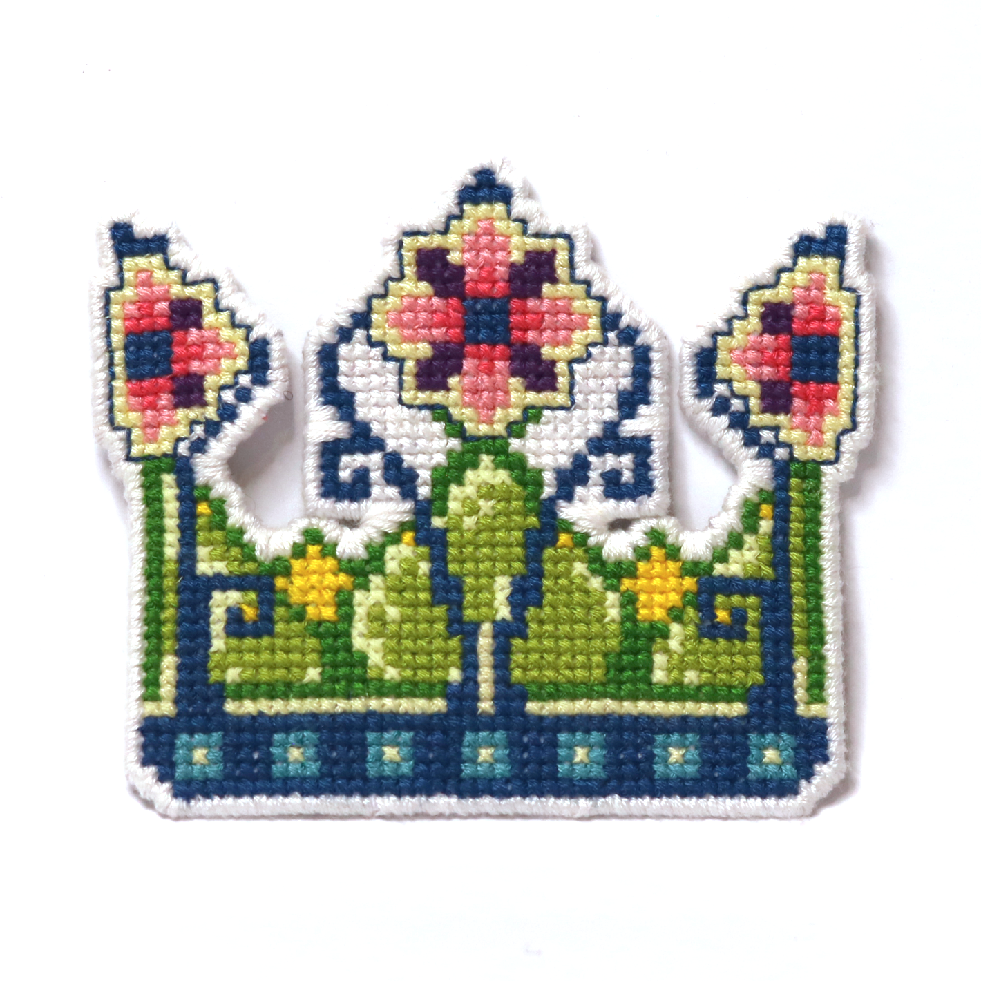 Cross-stitch fairy crown in green, blue, yellow, and pink with floral details.