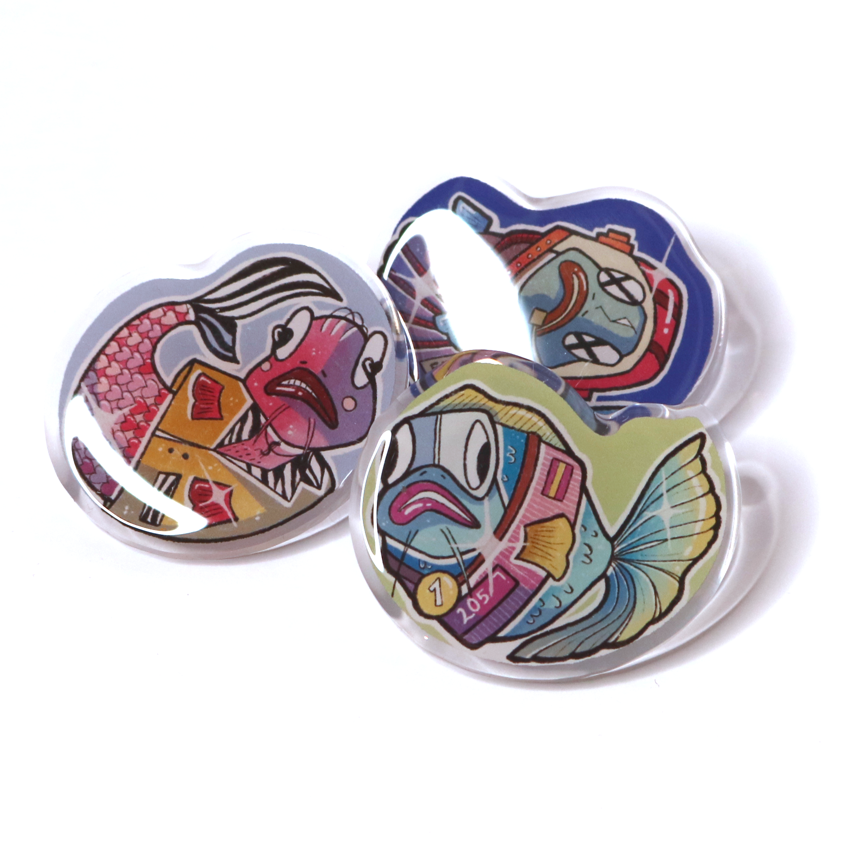 Acrylic pin set of all crafting wizard fish designs displayed together on a white background, showing three cute stylized fish acrylic pins.