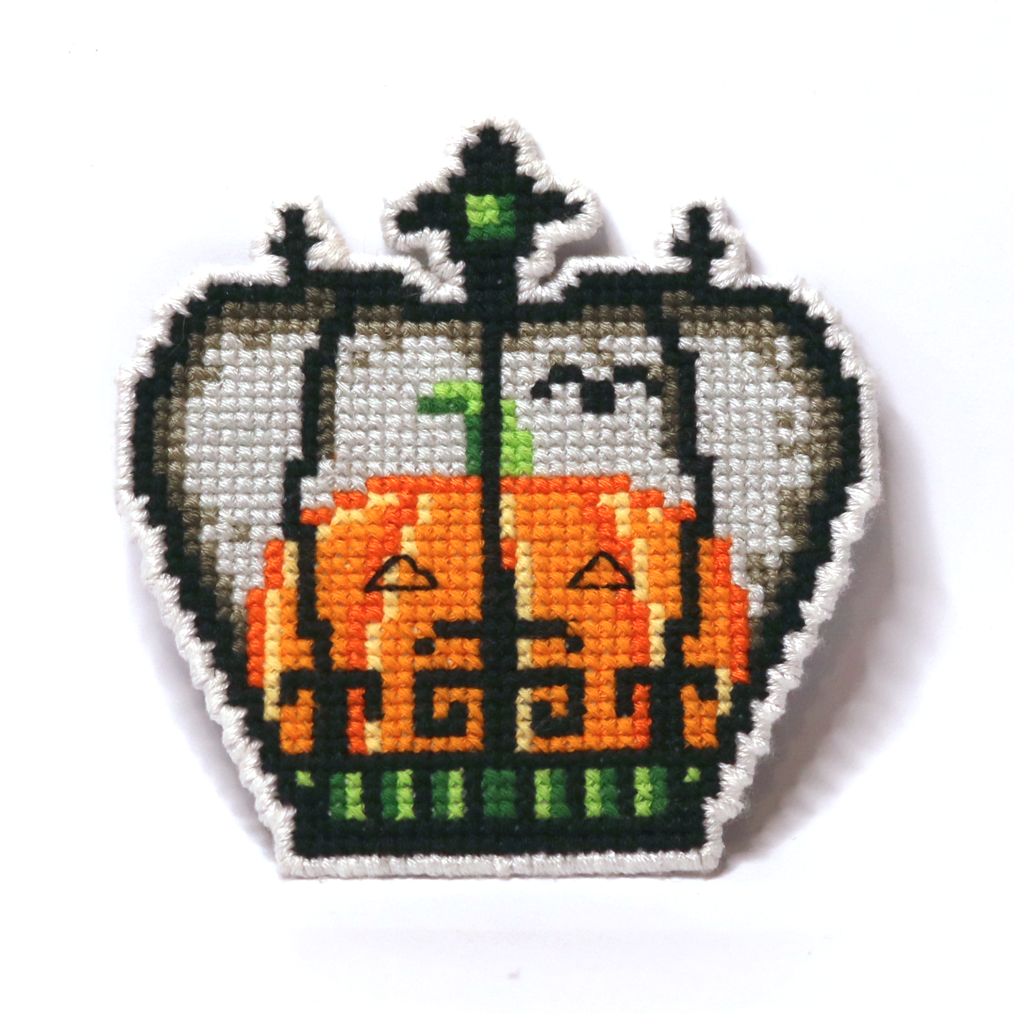 Cross-stitch Halloween crown in gray, orange, and green with a pumpkin and bird in Tim Burton style.