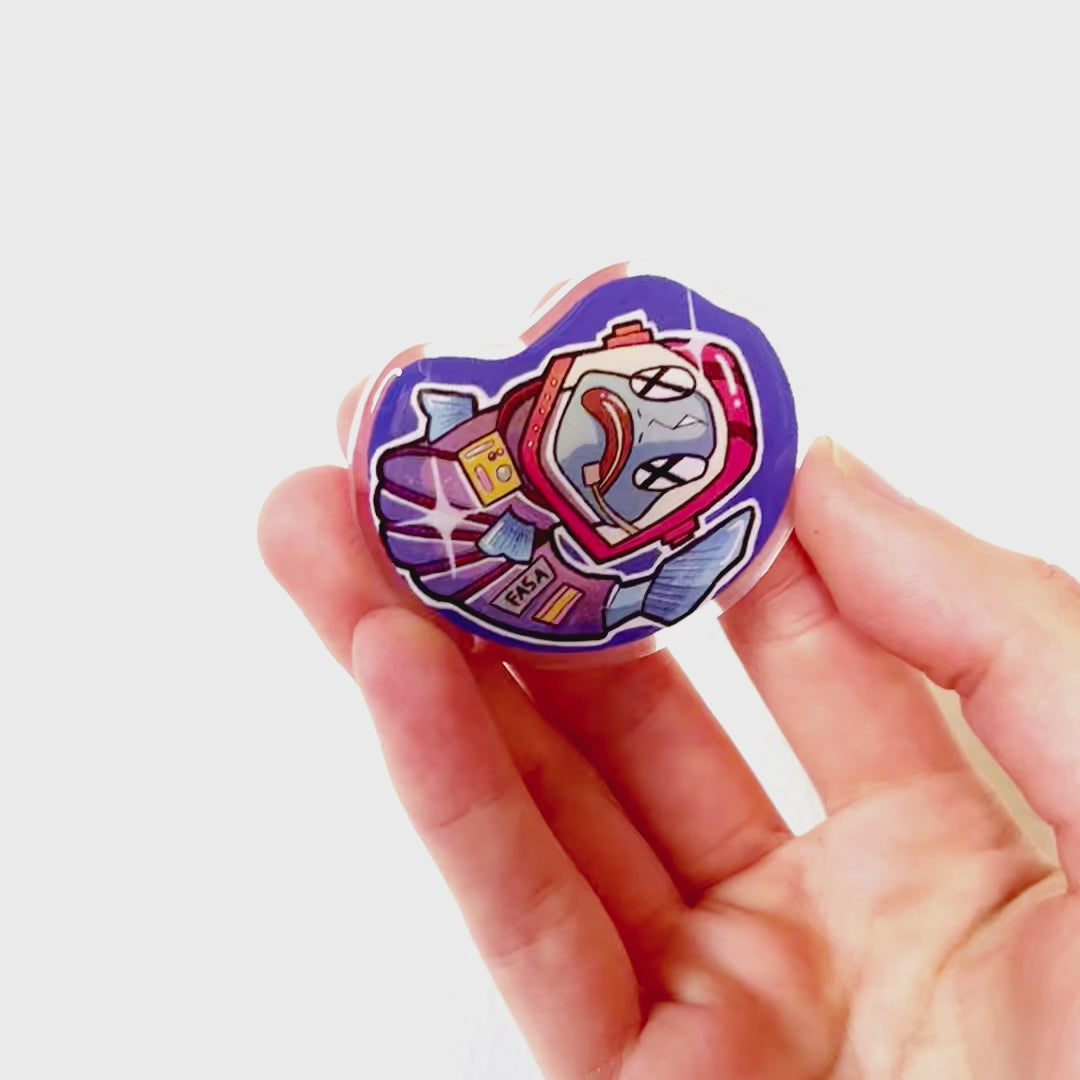 Video: Acrylic pin of an astronaut fish floating upside down in space, wearing a cracked helmet and spacesuit, giving a lifeless, eerie look.