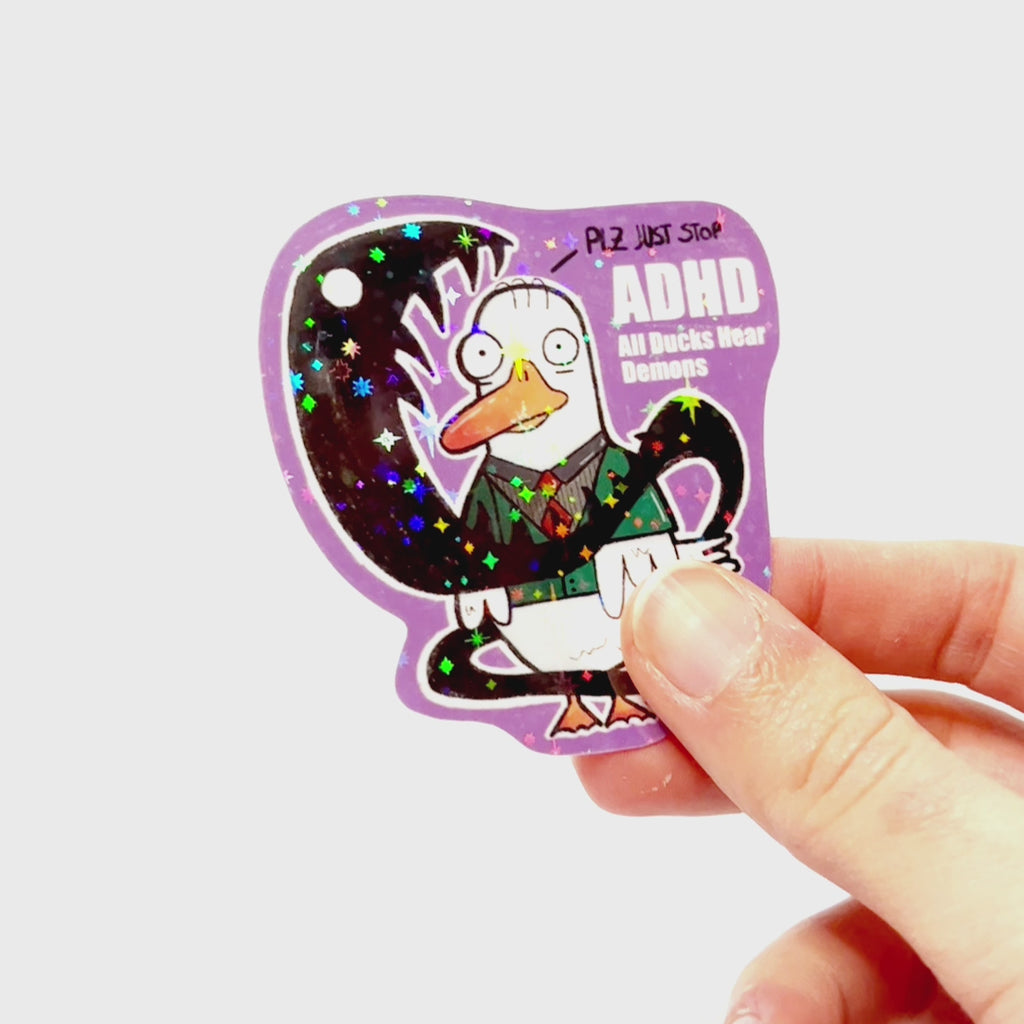 Video: Sticker of a confused duck in an anime-style school outfit surrounded by a dark demon, with the slogan ‘ADHD – All Ducks Have Demons.’